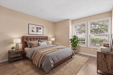 A bedroom with a large bed and a window with blinds.