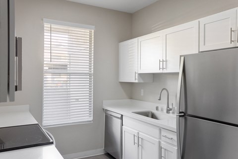 A kitchen with white cabinets and a stainless steel refrigerator.