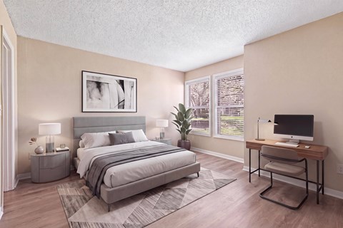 A bedroom with a large bed, a desk with a computer, and a chair.