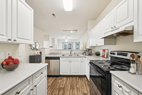 A modern kitchen with white cabinets and a black stove top oven.