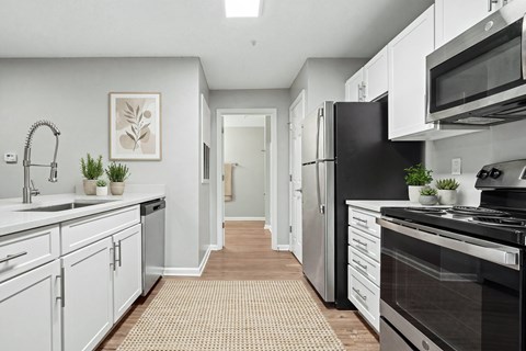 A kitchen with white cabinets and black appliances.