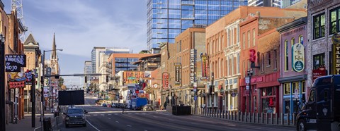 A city street with buildings on either side and a truck driving down the road.