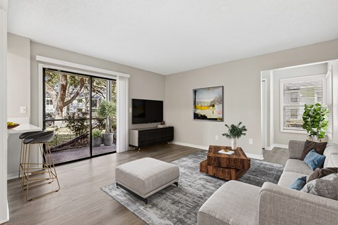 A living room with a grey couch, a white chair, a wooden coffee table, and a painting on the wall.
