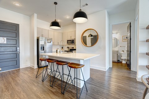 A kitchen with a white counter and bar stools.