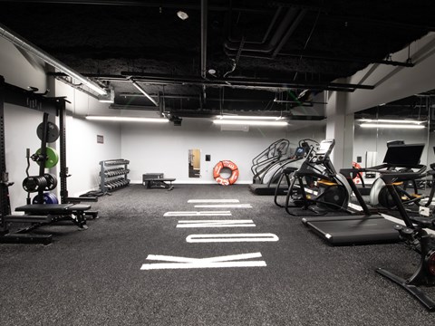 A gym with a variety of equipment including weights, a treadmill, and a stationary bike.