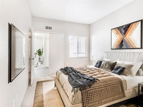 A bedroom with a bed covered in a blanket and pillows.