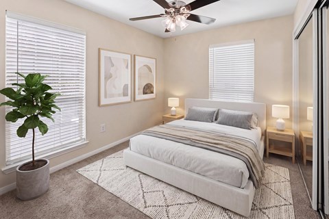 A bedroom with a large bed, a ceiling fan, and a potted plant.