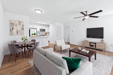 A modern living room with a grey couch and a wooden dining table.