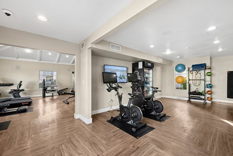 A spacious home gym with wooden floors and a variety of exercise equipment.
