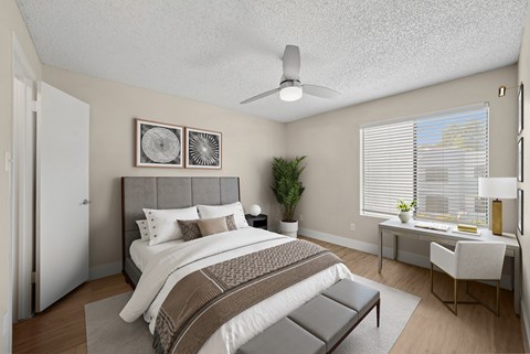 A bedroom with a large bed and a desk with a chair.