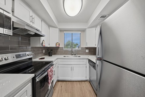 A kitchen with white cabinets and black appliances.