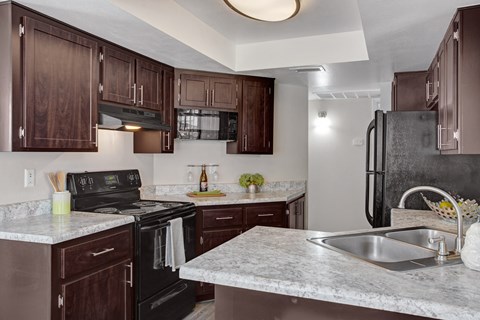 A kitchen with brown cabinets and a black stove top oven.