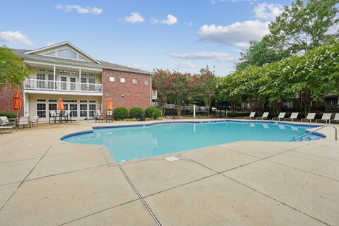 A large swimming pool in front of a building with a red brick exterior.