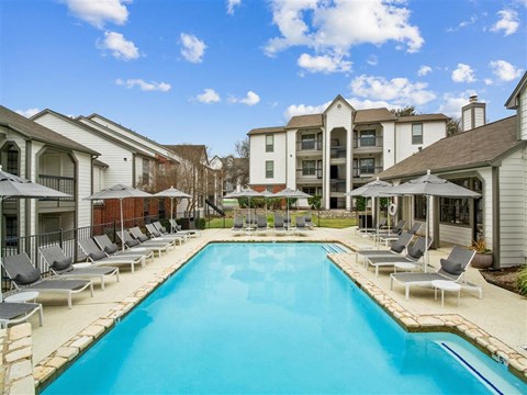 a swimming pool with chairs and umbrellas next to a building