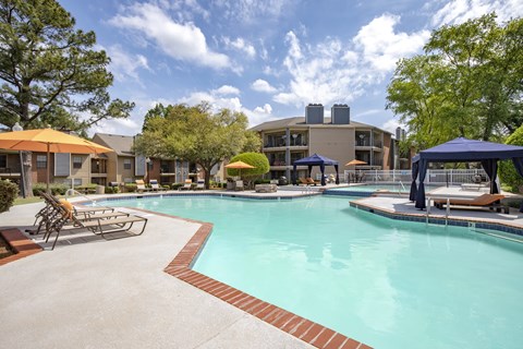A large swimming pool with a red brick border and a blue canopy.
