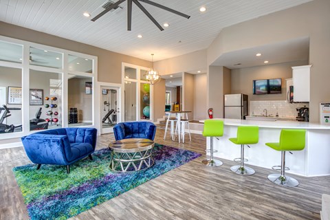 A living room with a blue chair and green chairs.