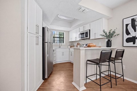 A kitchen with white cabinets and a black fridge.