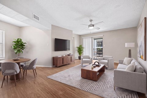 A living room with a grey couch, a wooden coffee table, a television, and a dining table with chairs.