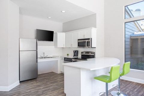 A modern kitchen with a white island and green bar stools.