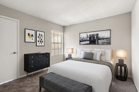 A bedroom with a large bed, a bench, and two lamps.