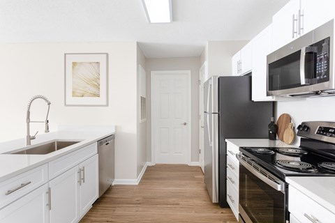 A kitchen with white cabinets and black appliances.