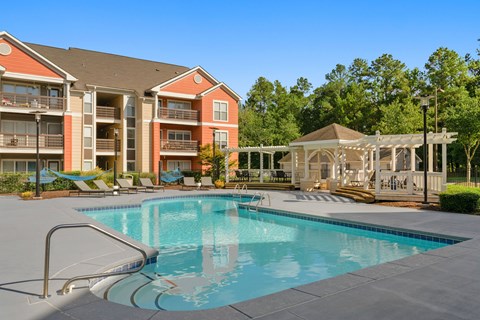 A swimming pool in front of a building with a gazebo in the background.