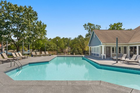 a swimming pool with chairs and a house in the background