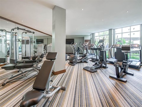 A gym with a variety of equipment including treadmills, weights, and exercise machines.