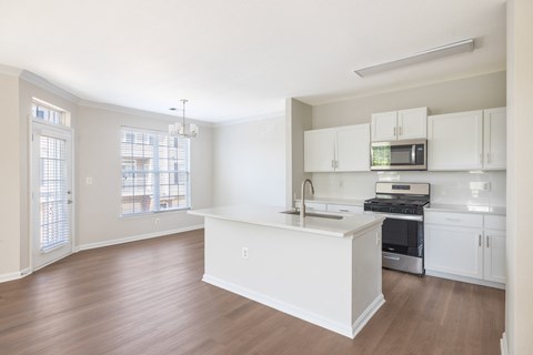 A kitchen with white cabinets and a wooden floor.