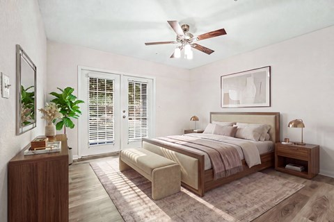 A bedroom with a bed, nightstand, and a plant.