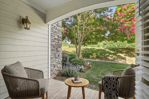 A patio with a table and chairs overlooking a garden.