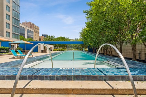 A blue tiled pool surrounded by trees and buildings.