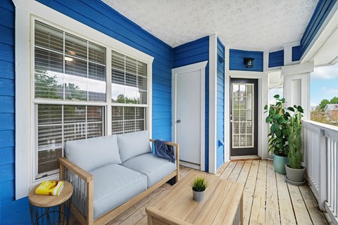 An apartment spacious balcony with blue exterior with a grey sofa and coffee table.