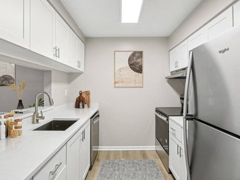 A kitchen with white cabinets and a fridge.