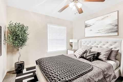 A bedroom with a large bed and a ceiling fan.