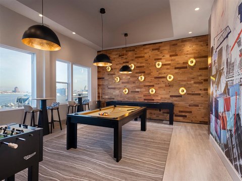 A billiard table is in the middle of a room with a wooden wall and a pool table on the left.