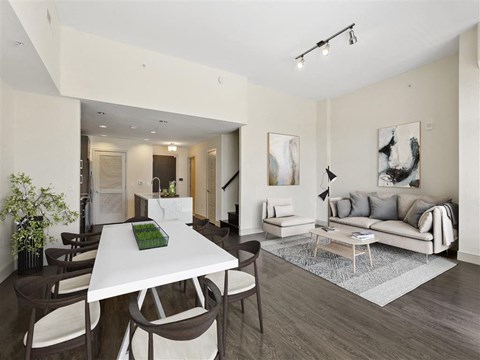 A modern living room with a white dining table and brown chairs.