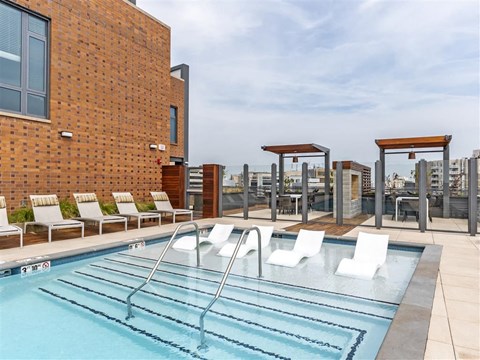 a swimming pool on the rooftop of a building with chairs