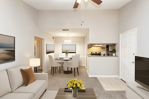 A living room with a white couch, a dining table, and a television.