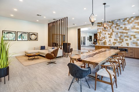 A modern dining room with a long wooden table and chairs.