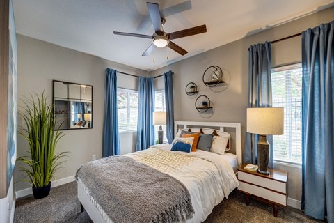 A bedroom with a large bed and a ceiling fan.