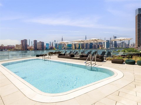 a pool on the roof of a building with a city in the background