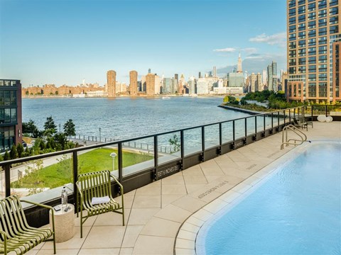 A pool on a balcony overlooking a city skyline.