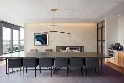 A modern dining room with a long table and chairs.