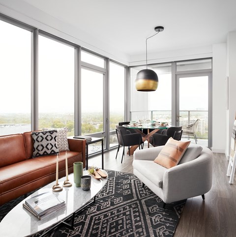 A living room with a brown leather couch and a grey armchair.