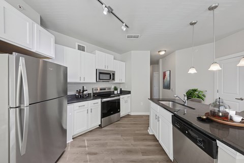 A modern kitchen with a stainless steel refrigerator and black countertops.