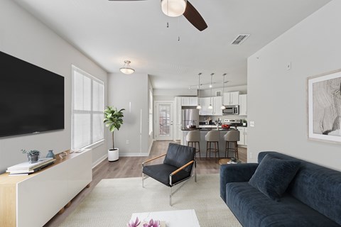 A living room with a black couch and a television on the wall.