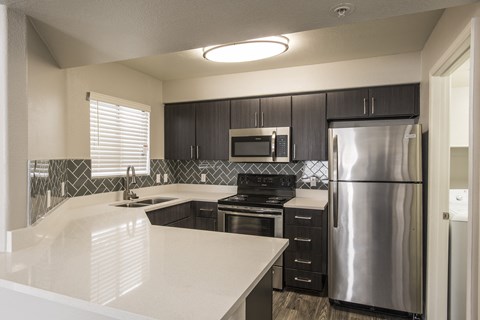 A modern kitchen with a stainless steel refrigerator and black cabinets.