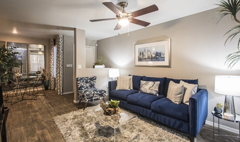 A living room with a blue couch and a ceiling fan.