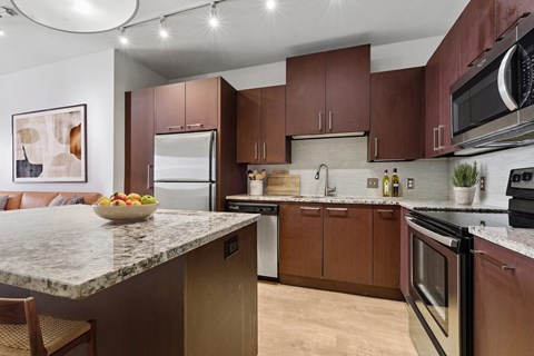 A kitchen with brown cabinets and a marble countertop.